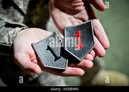 U.S. Army 2nd Lt. James Twigg, a battalion targeting officer with the 1st Combined Arms Battalion, 63rd Armor Regiment, 2nd Armored Brigade Combat Team, 1st Infantry Division, out of Fort Riley, Kan., holds up his 'Big Red One' unit patch and the subdued combat patch after a ceremony at the turf fields, Camp Lemonnier, Djibouti, July 27, 2013. About 350 soldiers were presented their combat patch during the ceremony. Only soldiers who have deployed to a combat zone are authorized to wear a patch on their right shoulder. (U.S. Air Force photo/Tech. Sgt. Chad Thompson) Stock Photo