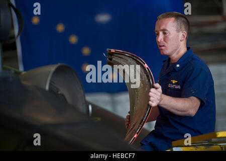 U.S. Coast Guard Petty Officer 3rd Class Travis Bird, puts an engine panel back on a HH-65B Dolphin helicopter after completing routine seven day maintenance inspection, June 26, 2012, at Coast Guard Air Station Kodiak, Alaska. Stock Photo