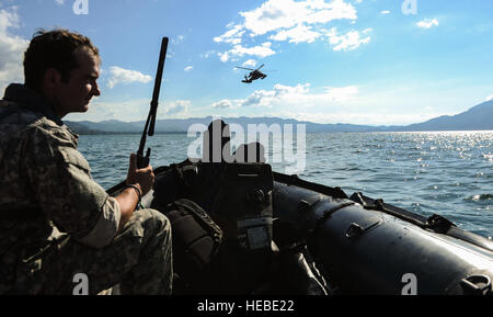 A member of U.S. Army Special Operations Forces communicates with the pilots of a UH-60 Black Hawk helicopter assigned to the 1-228th Aviation Regiment during hoist training at Lake Yojoa, Honduras, Jan. 22, 2015. The 1-228th Aviation Regiment partnered with U.S. Army Special Operations personnel to practice recovering live personnel. The overwater hoist training was held to ensure members of Joint Task Force-Bravo are planning and preparing for crisis and contingency response, as well as countering transnational organized crime, and counterterrorism operations as part of U.S. Southern Command Stock Photo