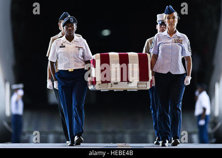 U.S. Army Pfc. Shantilla Robinson (left front), U.S. Air Force Chief Master Sgt. Laura Noel (right front), U.S. Navy Petty Officer 3rd Class India Davis (back left) and U.S. Marine Cassie McDole (back right) escort a flag-draped transfer case from a U.S. Air Force C-17 Globemaster III during the U.S. Joint POW/MIA Accounting Command Arrival Ceremony, Nov. 30, 2012, at Joint Base Pearl Harbor-Hickam. The U.S. personnel whose identities remain unknown are transported to JPAC's Central Identification Laboratory for analyses. The remains receiving full military honors represent losses associated w Stock Photo