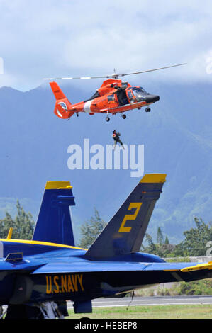 A U.S. Coast Guard Sailor hangs suspended in the air by an HH-65C/MH-65C Dolphin helicopter while demonstrating water rescue operations during the 2010 Kaneohe Bay Air Show at Marine Corps Base Hawaii in Kailua, Hawaii, Sept. 25, 2010. The air show, recently held every three years, also features aerial performances by Red Bull stunt teams, a C-17 Globemaster III aircraft, an F-22 Raptor aircraft with an aerial demonstration team from Langley Air Force Base, Va., and the U.S. Navy Flight Demonstration Squadron, the Blue Angels. (U.S. Air Force photo by Tech. Sgt. Cohen A. Young/Released) Stock Photo