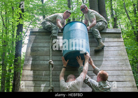 U.S. Airmen with the Vermont Air National Guard navigate the Leadership Reaction Course, working in pairs to get a large barrel representing supplies over a steep wall at Camp Ethan Allen Training Site, Jericho, Vt., June 4, 2016. Each group was given 25 minutes to plan and overcome the different obstacles.  (U.S. Air National Guard photo by Staff Sgt. Victoria Greenia/Released) Stock Photo