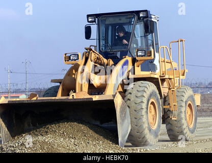 A US Air Force airman from the 51st Civil Engineers Squadron, Osan Air Base, Republic of Korea uses a front-end loader to move dirt and rocks during a runway repair exercise, part of the Operational Readiness Inspection. Stock Photo