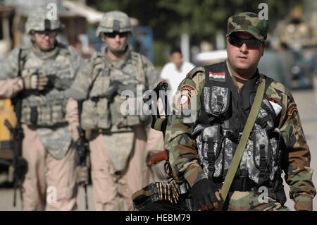 Security personnel accompany an Iraqi national policeman of the criminal investigations division on a walking patrol. They are meeting Iraqi civilians and handing out leaflets in the Rashid community of southern Baghdad, Iraq, December 2008. The Airmen are assigned to Detachment 3, 732 Expeditionary Security Forces Squadron with the 716th Military Police Battalion. (U.S. Navy photo/Petty Officer 2nd Class Todd Frantom) Stock Photo