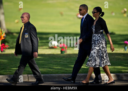 Retired U.S. Marine Corps Col. Gene Castagnetti, cemetery director, escorts President Barack Obama and first lady Michelle Obama to their seats as they arrive at the National Memorial Cemetery of the Pacific for a Dec. 23, 2012 memorial service in honor of Sen. Daniel K. Inouye. Inouye was a U.S. Army World War II combat veteran with the 442nd Regimental Combat Team, who earned the nation's highest award for military valor, the Medal of Honor. Inouye became Hawaii's first congressman following statehood in 1959; he won election to the Senate in 1962. He was the first Japanese-American elected  Stock Photo
