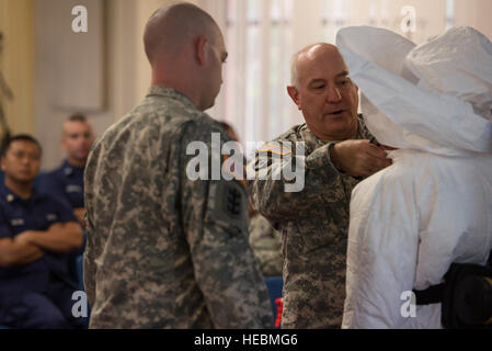 U.S. Army Lt. Col. Neal Woollen (center), United States Army Medical Research Institute of Infectious Diseases (USAMRIID) director of bio security, and U.S. Army Sgt. Daniel Vita (left), USAMRIID combat medic, show students how to don personal protective equipment with the help of U.S. Army Pfc. Kaiya Capuchino, USAMRIID combat medic, during hazardous material training Oct. 30, 2014, at Tripler Army Medical Center, Hawaii. Members of the USAMRIID conducted the class to help ensure service members and civilians are better prepared to react to and defend themselves against infectious diseases at Stock Photo