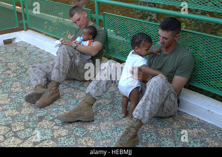 DJIBOUTI - During a visit to the Djibouti baby orphanage Jan. 26, Marine 1st Lts. James D. Lasley (left) and Tim J. Lockhart (right) play with orphans after assisting French nuns feed the young children dinner. Lockhart, an Arlington, Va., native, is the Bravo Battery platoon commander for the 3rd Low Altitude Air Defense Battalion. Lasley, a Portland, Texas, native, is the Alpha Battery 3rd LAAD executive officer. The battalion is deployed from Camp Pendleton, Calif. The Marines are currently deployed to provide security to Camp Lemonier, Djibouti. Stock Photo