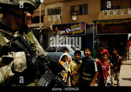 U.S. Army 1st Lt. Michael Brabner, a native of  Bay Mimtte, Ala.,smiles at the children next him as he pulls security for the Ghazaliyah patrol police officers as they post wanted posters and hand out pamphlets to Iraqi citizens in a neighborhood of Ghazaliyah, Iraq on Sep. 4, 2008. The U.S. Soldiers are part of 3rd Platoon, Bravo Company, 1st Squadron, 75th Cavalry, 101st Airborne Division. Stock Photo