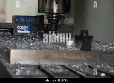 A computer numeric controller router creates a C-130 Hercules crew door arm clamp in the fabrication shop at Yokota Air Base, Japan, June 23, 2015. A CNC router is a computer controlled cutting machine related to the hand held router used for cutting various hard metals, such as wood composites, aluminum, steel, plastics and foams. (U.S. Air Force photo by Senior Airman David Owsianka/Released) Stock Photo