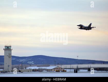 One of 14 U.S. Air Force F-16 Fighting Falcon aircraft with the 18th Agressor Squadron takes off from Eielson Air Force Base, Alaska, shortly after sunrise Jan. 17, 2015, in transit to Hickam Air Force Base, Hawaii, and Andersen Air Force Base, Guam to participate in the CENTURY ALOHA and COPE NORTH exercises. More than 150 maintainers will keep the Agressors in the air during the exercises, which are meant to prepare U.S. Airmen, Sailors and Marines along with coalition partners in the Pacific theater of operations for contingency operations if the need arises. Stock Photo