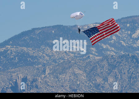 A member of the Wings of Blue U.S. Air Force Skydiving Team descends with an American Flag toward show center of the Thunder and Lightning over Arizona Open House at Davis-Monthan Air Force Base, Ariz., March 13, 2016. The demonstration team travels across the country to airshows, sporting events, and other venues to represent the Air Force in precision parachuting. (U.S. Air Force photo by Senior Airman Chris Massey/Released) Stock Photo