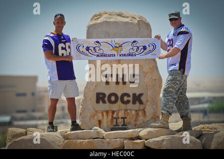 In anticipation of the upcoming NFL regular season kickoff, Minnesota Vikings fans and deployed U.S. soldiers Chief Warrant Officer 4 Joel Gordon and Spc. Lance Nielsen pose for a photo at the 386th Air Expeditionary Wing's 'Rock' monument proudly wearing their Vikings jerseys, Sunday, Aug. 25, 2013. Gordon, a Dassel, Minn. native, is a C-12 pilot stationed with Detachment 51 at Joint Base Lewis-McChord. He currently lives in Washington state. Nielsen, a St. Paul, Minn., native, is an aviation operations specialist with Detachment 39 at Army Aviation Support Facility Number 1 of the Minnesota  Stock Photo