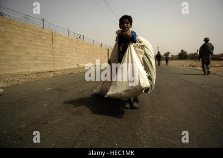 An Iraqi boy passes U.S. Soldiers as they head back to Joint Security Station Shula, Iraq, after a mission on July 19, 2008. The U.S. Soldiers are part of 2nd Platoon, Bravo Company, 1st Battalion, 502nd Infantry Regiment, 101st Airborne Division. (US Air Force photo by Staff Sgt. Manuel J. Martinez/Released) Stock Photo