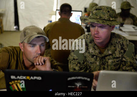 U.S. Navy Mass Communication Specialist 1st Class Patrick Mullen III, left, assigned to Expeditionary Combat Camera, and Chief Mass Communication Specialist Mark Schultz, assigned to Fleet Combat Camera Pacific, edit photos Aug. 25, 2014, during Summer Quick Shot 2014 in the Angeles National Forest in Azusa, Calif. Quick Shot is a semiannual field exercise designed to train combat camera personnel to operate in a combat environment. (U.S. Air Force photo by Senior Airman Thomas Smith/Released) Stock Photo