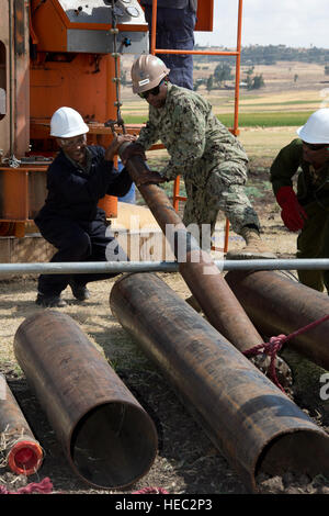 Mr. Solomon Lambebo Chinketo, Ethiopian National Defense Force water well drilling instructor, and U.S. Navy Petty Officer 1st Class Evanthony Stevenson, Naval Mobile Construction Battalion 1 equipment operator, secure a drill bit during water well drilling operations in Fiche, Ethiopia, Dec. 19, 2012. NMCB 1 Seabees attached to Combined Joint Task Force-Horn of Africa partnered with ENDF engineers during a water well drilling exercise beginning Nov. 27, 2012. The exercise strengthened the operational and institutional capabilities of the ENDF and helped build the relationship between the two  Stock Photo