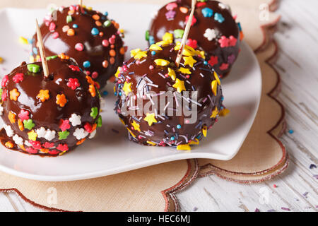Fresh apples in chocolate with candy sprinkles on a white plate. horizontal Stock Photo