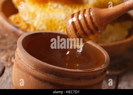 Liquid flower honey dripping from a stick in a jar macro. Horizontal Stock Photo