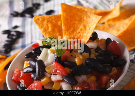 Mexican salsa with black beans in a bowl and corn chips nachos macro. horizontal Stock Photo