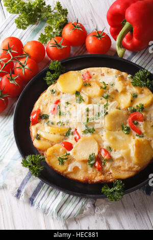 Delicious Spanish tortilla on a black frying pan close-up. vertical Stock Photo
