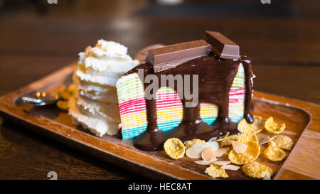 Rainbow crape cake with wipe cream and decoration on white plate. (Selective Focus) Stock Photo