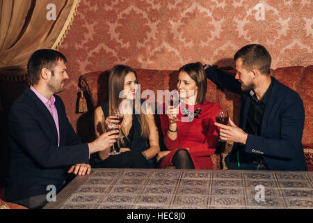 Two young couples in restaurant drinking wine Stock Photo