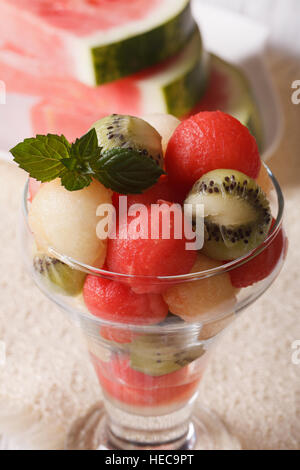 Fruit balls of watermelon, kiwi and melon with mint in a glass close up vertical Stock Photo