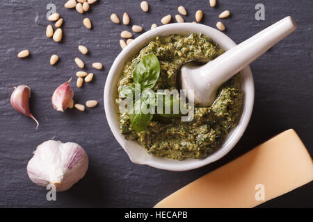 Italian green pesto sauce in a mortar and ingredients close-up on the table. horizontal view from above Stock Photo
