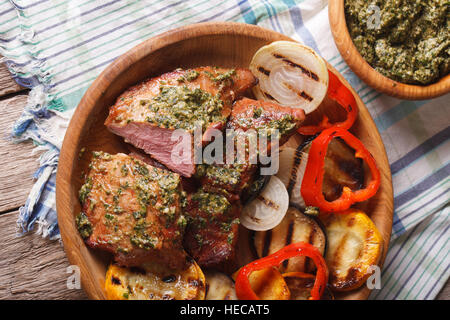 Veal meat and grilled vegetables with pesto sauce close-up on a plate. horizontal view from above Stock Photo