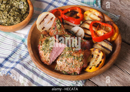 Veal meat and grilled vegetables with pesto sauce close-up on a plate. horizontal, rustic style Stock Photo