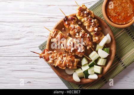 Chicken satay with a delicious peanut sauce and fresh salad on the plate. horizontal top view Stock Photo