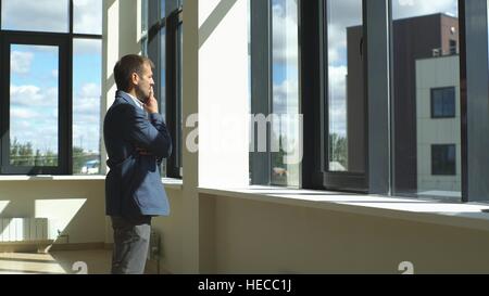 a successful businessman looks out the window and ponders the business plan Stock Photo