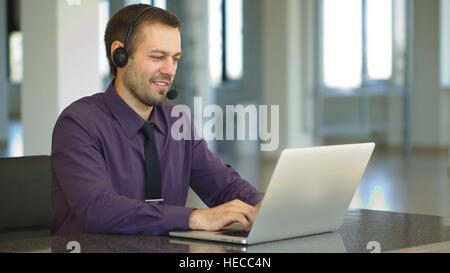 Focus on a joyful call centre agent with his headset Stock Photo