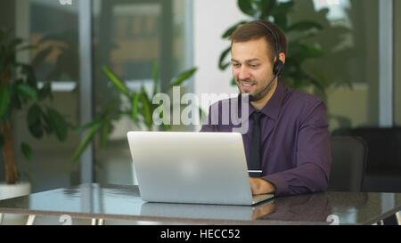 Smiling businessman with headset interacting in his office Stock Photo