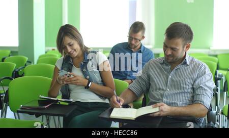 smiling young male student with others writing notes in the classroom Stock Photo