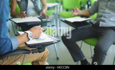 document with charts on background of male and female hands with pens over open notebooks Stock Photo