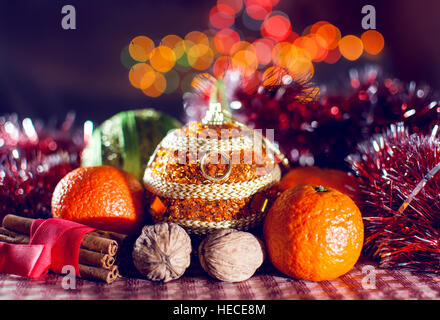 Image of New Year's decoration, balls, tinsel, cinnamon, mandarins, walnuts on the background of lights bokeh. Low key. Selective focus. Stock Photo