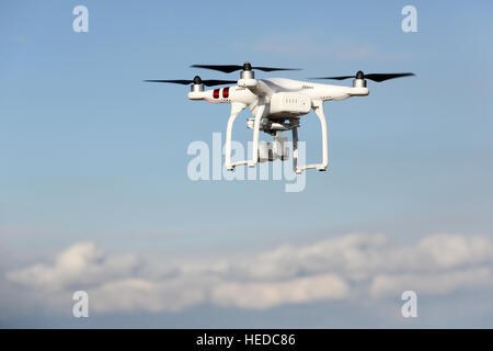 White remote controlled Drone Dji Phantom 3 equipped with high resolution video camera hovering in air and blue sky Stock Photo