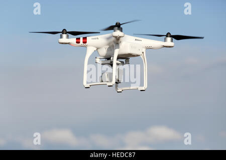 White remote controlled Drone Dji Phantom 3 equipped with high resolution video camera hovering in air and blue sky Stock Photo