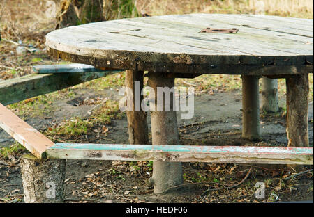 round wooden table with benches in the woods Stock Photo