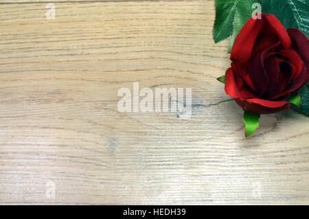 Red rose with wedge leaves on a brown wood background Stock Photo
