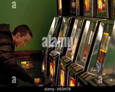 Playing the fruit machines in an arcade Stock Photo