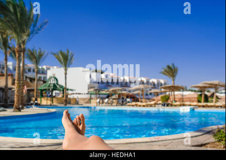 womans feet against swimming pool on resting Stock Photo
