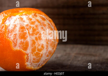 Close up of one peeled orange on the wooden background with copy space Stock Photo