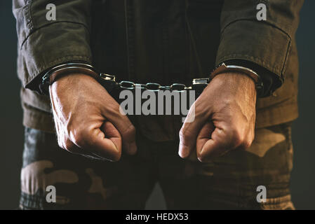 Handcuffed soldier, arrested male army officer in dark prison cell Stock Photo
