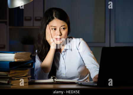 asian business woman sitting at desk sleepy working overtime late night. indoors office background Stock Photo