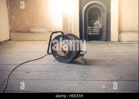 An extension cord in a sunny and empty room with a Victorian fireplace Stock Photo