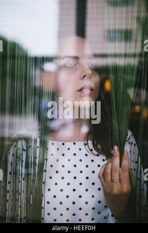 Woman standing behind window Stock Photo