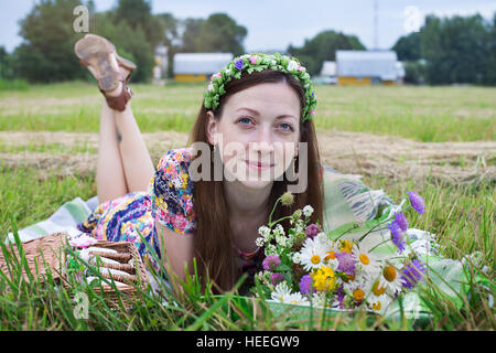 Freckled girl lying on plaid in meadow Stock Photo