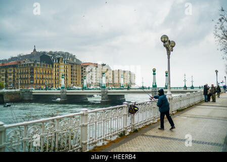 A woman fishes from the boardwalk on a cold winters day in San Sebastian