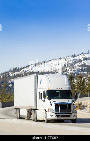 White Semi Truck 18-Wheeler on snowy mountain pass. Stock Photo